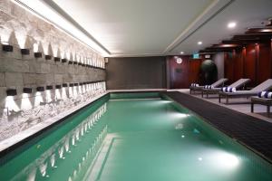 a swimming pool in a hotel room with chairs at The Nishat Hotel in Lahore