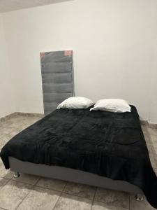 a bed with a black comforter and two pillows at Departamento independiente en Juárez in Ciudad Juárez