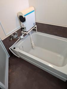 a bathtub with a hair dryer sitting on the floor at Abashiri Ryuhyou no Oka guesthouse in Abashiri +36 photos