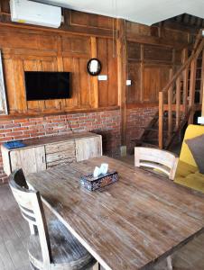 a wooden table with chairs and a television in a room at Melasti Mountain Villas Amed in Amed