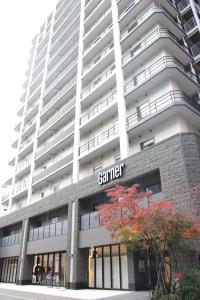 a tall white building with a sign on it at Garner Hotel Osaka Honmachi Station by IHG in Osaka