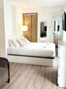 a white bedroom with a large bed and a living room at Grand Central House - Classic One Bedroom - GibraltarStay Apartments in Gibraltar