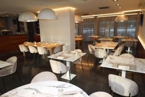 ein Restaurant mit Tischen und weißen Stühlen und Tischen und Tischsuche in der Unterkunft One Hotel & Restaurant in Dalmine