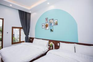 two beds in a room with a blue wall at Nắng House MỘC CHÂU in Mộc Châu