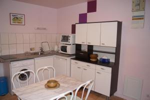 a kitchen with white cabinets and a table with chairs at Le Sel J'm in Salins-les-Bains