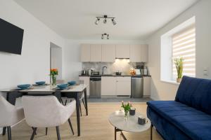 a living room with a blue couch and a kitchen at Apartamenty przy Stoku in Krynica Zdrój +25 photos