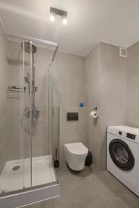 a bathroom with a shower toilet and a washing machine at Apartamenty przy Stoku in Krynica Zdrój