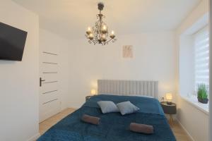 a bedroom with a blue bed and a chandelier at Apartamenty przy Stoku in Krynica Zdrój