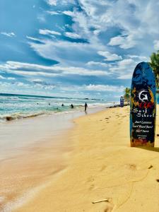 una tabla de surf en una playa con gente en el agua en Soldara Gedara, en Hikkaduwa
