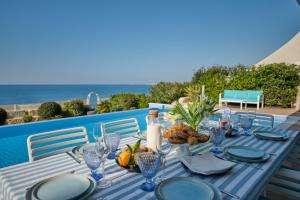 a blue and white table with food and the ocean at Olymp Luxury Villa C - Seafront Elegance with Infinity Pool and Exclusive Lifestyle in Kissonerga +74 photos