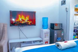 a room with a tv on a wall with a fireplace at Haydenco Suites Signatuture Mall Syokimau in Nairobi