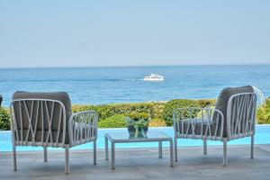 基索内加Olymp Luxury Villa C - Seafront Elegance with Infinity Pool and Exclusive Lifestyle的海景庭院设有两把椅子和一张桌子