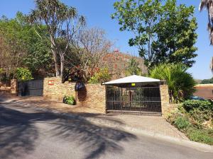 a brick fence with a gate with an umbrella at The Green Lizard Self-catering House in Nelspruit