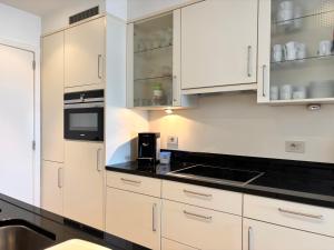 a kitchen with white cabinets and black counter tops at Windjammer A3 - Sea View in Koksijde +18 photos