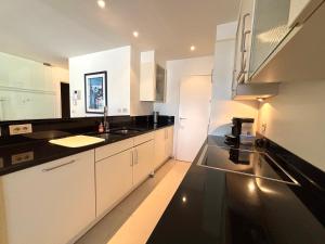 a kitchen with white cabinets and black counter tops at Windjammer A3 - Sea View in Koksijde