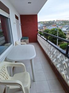 a white table and chairs on a balcony with a view at Apartamento frente a la Playa in Suances