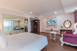 - une chambre avec un grand lit blanc et un canapé violet dans l'établissement Bonjour Nha Trang Hotel, à Nha Trang