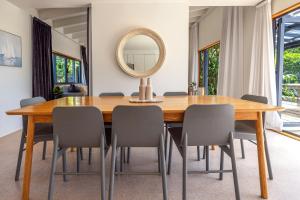 - une table à manger avec des chaises et un miroir dans l'établissement Oneroa Sanctuary - Be My Guest Waiheke, à Waiheke Island