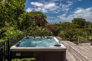 une baignoire jacuzzi sur une terrasse en bois dans l'établissement Oneroa Sanctuary - Be My Guest Waiheke, à Waiheke Island