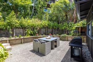 un patio avec une table et des chaises dans une cour arrière dans l'établissement Oneroa Sanctuary - Be My Guest Waiheke, à Waiheke Island