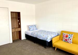 a bedroom with a bed and a yellow chair at Rotorua Stay in Rotorua