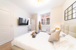 une chambre blanche avec un grand lit avec un ours en peluche dessus dans l'établissement La Tigresse Colmar Centre, à Colmar 2 autres photos