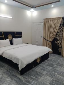 una camera da letto con un letto grande con lenzuola bianche di JS Rezidor a Islamabad