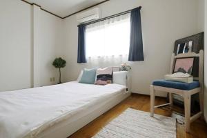 ein Schlafzimmer mit einem großen weißen Bett und einem Fenster in der Unterkunft Nakamichi House 中道戸建 in Osaka