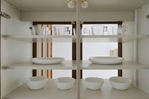 ein Regal mit weißen Schalen und Tassen darauf in der Unterkunft Nakamichi House 中道戸建 in Osaka + 74 Fotos