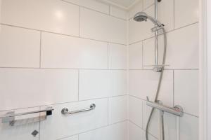 a shower in a bathroom with white tiles at Groenendijk Verhuur Vakantiewoning de Haerde 52 in Ellemeet in Ellemeet +19 photos
