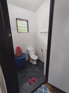 a bathroom with a toilet and a window and two slippers at Rizkie homestay in Tanah Rata
