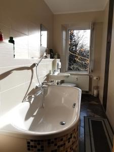 eine große weiße Badewanne im Bad mit Fenster in der Unterkunft Altstadt-Domizil in Annaberg-Buchholz