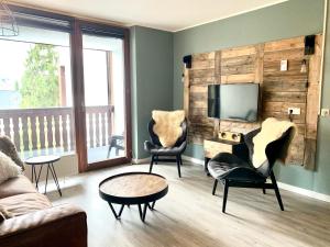 a living room with two chairs and a flat screen tv at Kappeberg Lodge in Winterberg