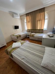 a room with three beds and a tv in it at Mimoza Pansiyon in Antalya