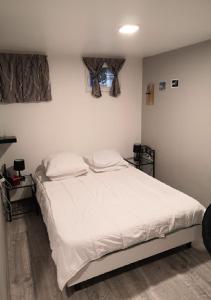 una camera da letto con un letto con lenzuola bianche e una finestra di Mini STUDIO a Marsannay-la-Côte