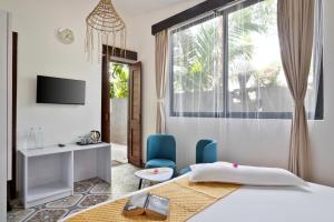 a bedroom with a bed and a desk and a window at Royale Amata By the Beach in Morjim