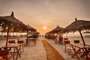a group of tables and straw umbrellas on a beach at Royale Amata By the Beach in Morjim