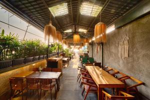 a restaurant with wooden tables and chairs and plants at Royale Amata By the Beach in Morjim