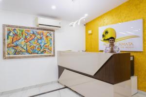 a man standing behind a counter in a room with a painting at Royale Amata By the Beach in Morjim