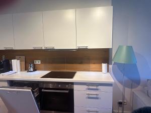 a kitchen with white cabinets and a sink and a lamp at Art & View - Apartment in Bad Gastein