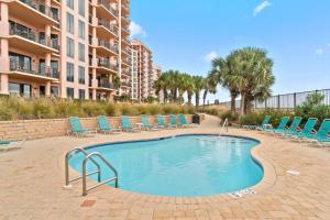 a swimming pool with lounge chairs and a building at Seachase 1503W in Orange Beach