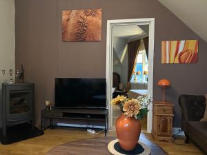 a living room with a television and a vase with flowers at Historical house with view and separate entrance in Ålesund