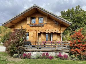 a log cabin with a porch and flowers in front of it at La Marmotte in Chorges