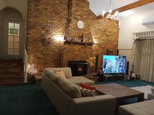sala de estar con sofá, TV y pared de ladrillo en Federation Style 4 bedroom House with Ocean View, en Lakes Entrance