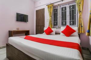a bedroom with a large bed with red pillows at Hotel O Ma Kali Guest House in Kolkata +26 photos