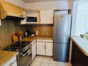 a kitchen with a stainless steel refrigerator and white cabinets at Villa Nini46 in Noumea