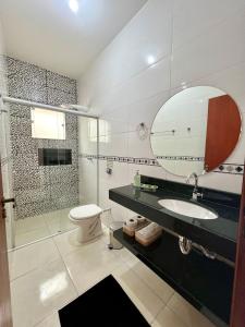a bathroom with a sink and a toilet and a mirror at Pousada Aconchego De São Thomé in São Thomé das Letras +51 photos