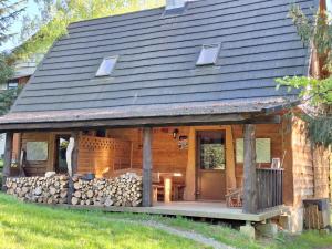 a log cabin with a porch and a pile of logs at Dwerniczówka in Dwernik