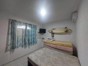 a room with two beds and a surfboard on the wall at Casa Praia Peruibe in Peruíbe +24 photos