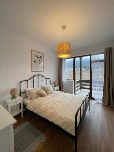 ブシュテニにあるMoolys riverside apartmentsのベッドと大きな窓のある寝室